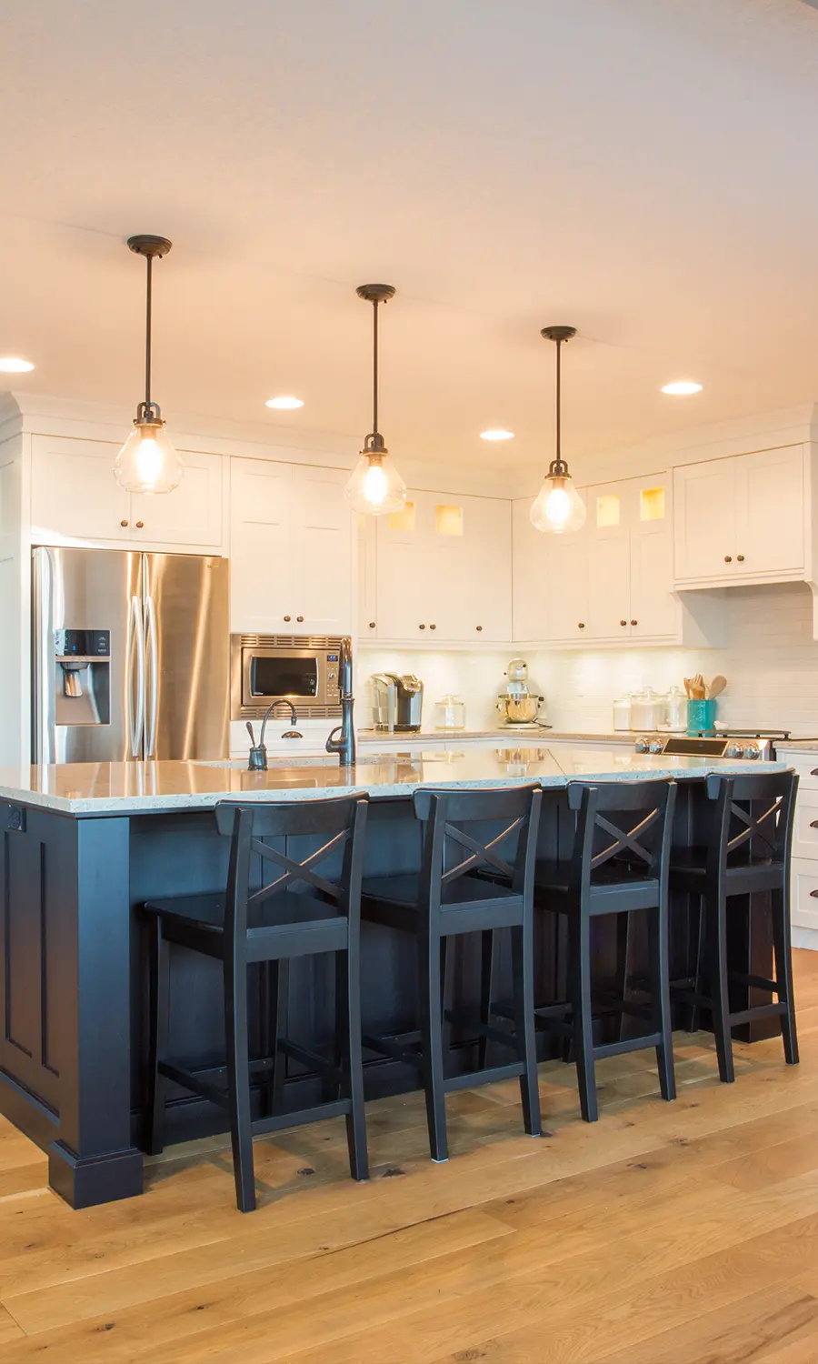 Modern kitchen lighting setup featuring pendant lights over island and recessed ceiling lights, enhancing ambiance and functionality.